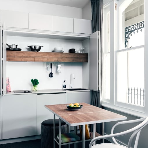a small kitchen with white cabinets and a wooden table
