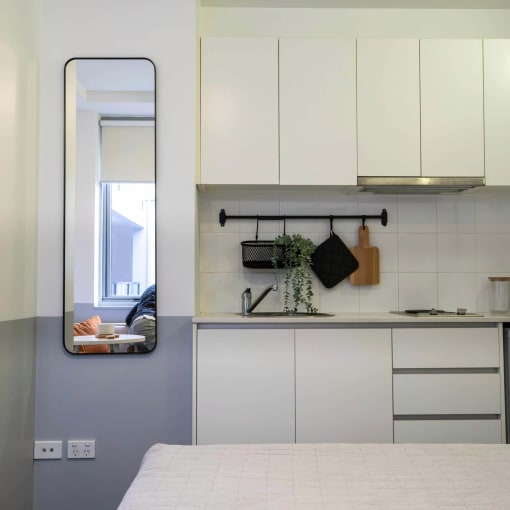 a kitchen with white cabinets and a mirror on the wall