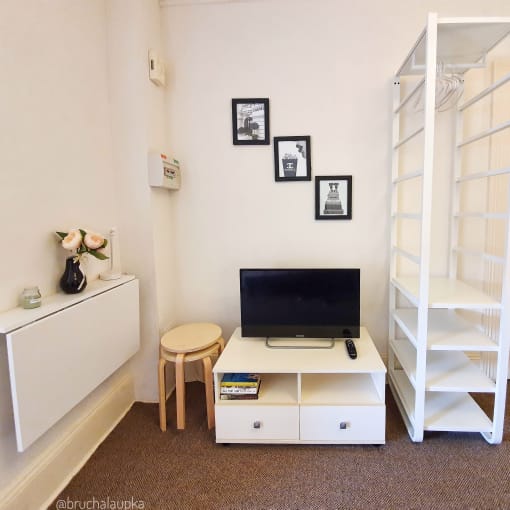 a living room with a tv and a white shelf