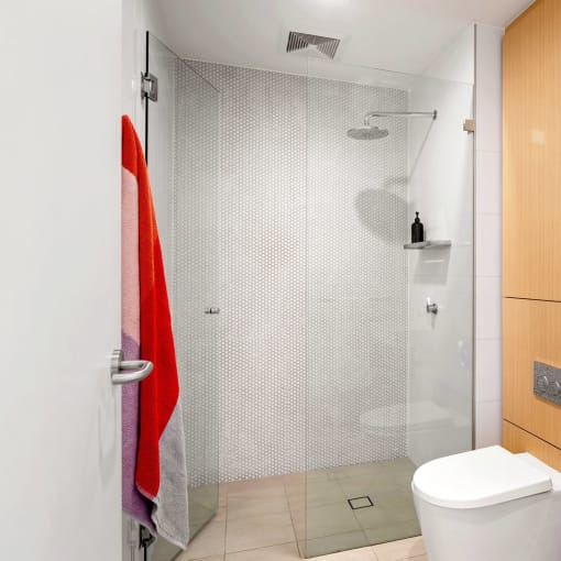 a bathroom with a shower and a wooden floor and white walls