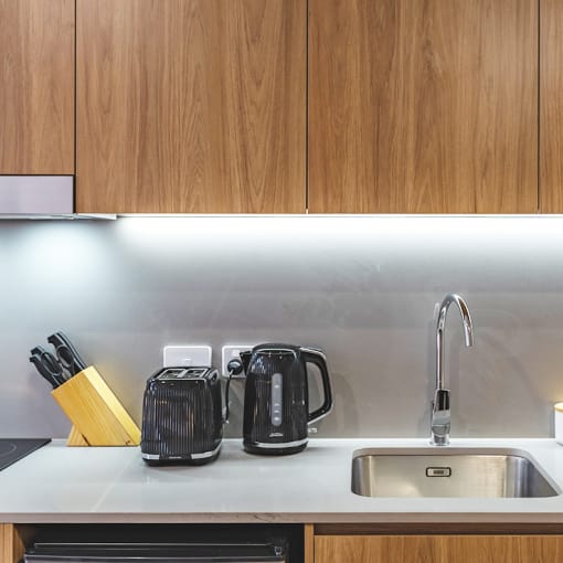 a kitchen counter with a sink and a kettle and a coffee maker
