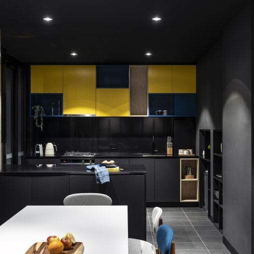 a black kitchen with yellow cabinets and a white table and chairs