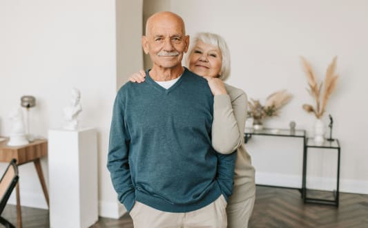 an older couple standing in a room with their arms around each other