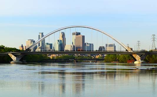 A bridge spans a body of water with a city skyline in the background.