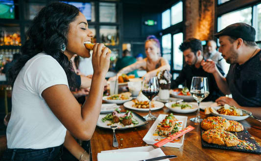 a group of people sitting at a table eating food at a restaurant