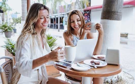 Two women are sitting at a table with drinks in front of them.