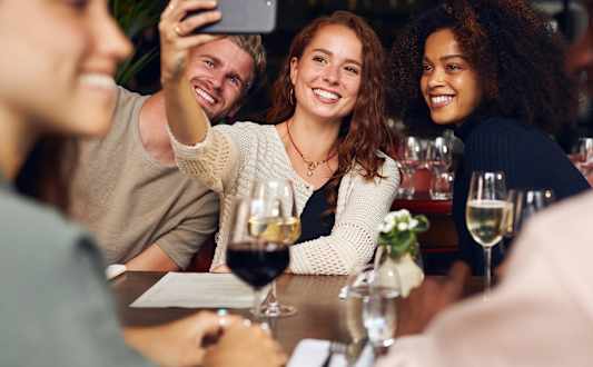 A group of people are taking a selfie at a wine bar.