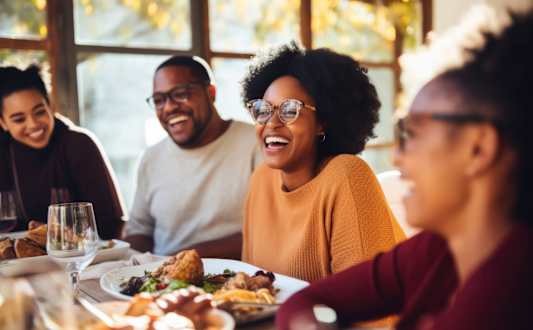 Four people are sitting at a table with food in front of them.