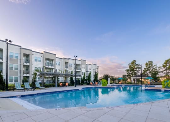 a swimming pool with an apartment building in the background at Linden on the GreeneWay, Florida, 32824
