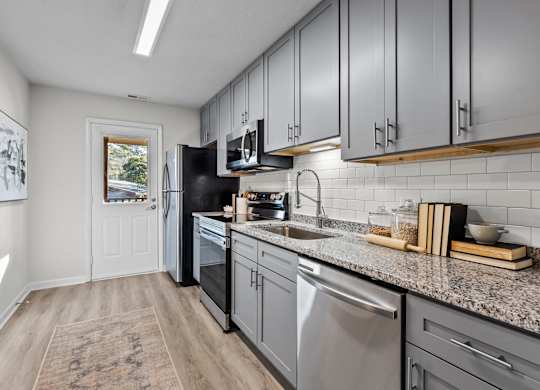 A kitchen with a black fridge and stainless steel dishwasher at West Oak Apartments, North Carolina 27587