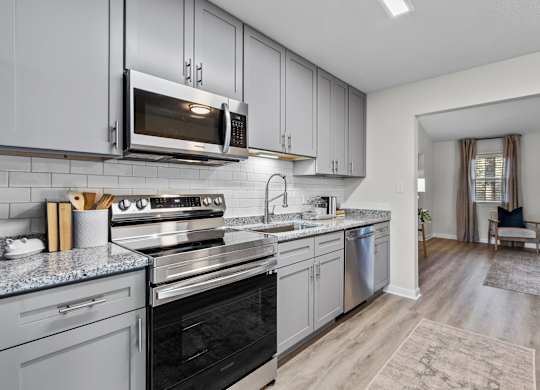 A modern kitchen with a black oven and grey cabinets at West Oak Apartments, Wake Forest, 27587