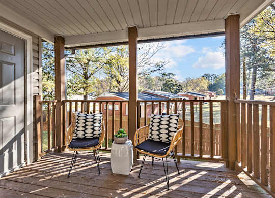 Two chairs on a porch with a pillow on the back of each chair at West Oak Apartments, Wake Forest