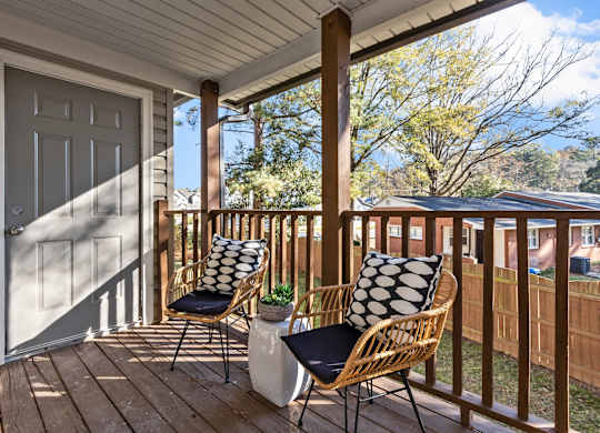 A wooden porch with two chairs and a table at West Oak Apartments, North Carolina 27587