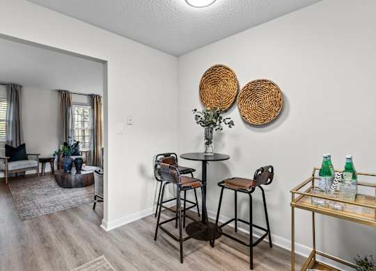 A living room with a bar stool and a table at West Oak Apartments, Wake Forest, NC