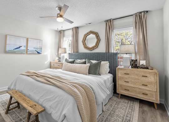 A bedroom with a bed, a bench, a dresser, and a ceiling fan at West Oak Apartments, Wake Forest, North Carolina