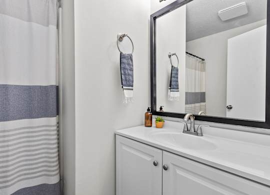 A bathroom with a white sink and a mirror at West Oak Apartments, Wake Forest