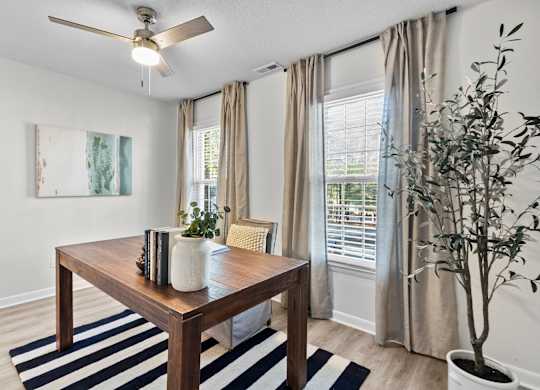 A room with a table, a plant, and a painting on the wall at West Oak Apartments, Wake Forest, North Carolina