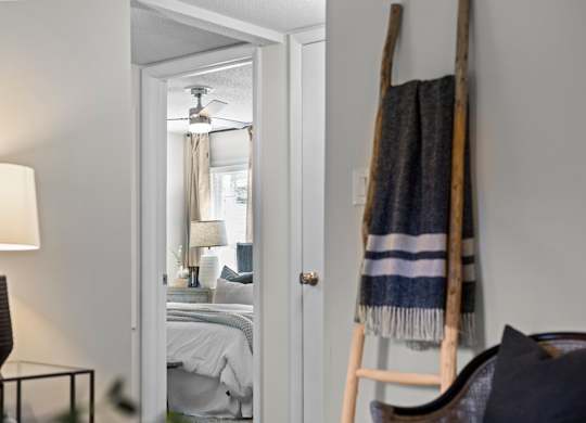 A bedroom with a bed, a lamp, and a blanket on a ladder at West Oak Apartments, Wake Forest