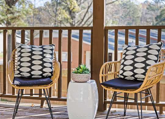 Two chairs with black and white pillows on a wooden balcony at West Oak Apartments, North Carolina