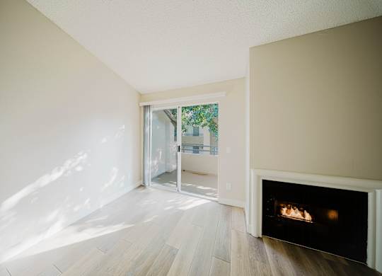 A room with a fireplace and a view of a tree-lined street through a glass door. at Legends at Rancho Belago, Moreno Valley, California