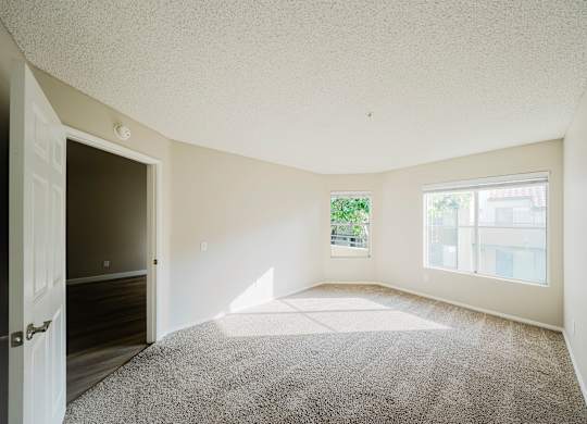 A room with a carpeted floor and a door leading to another room. at Legends at Rancho Belago, California