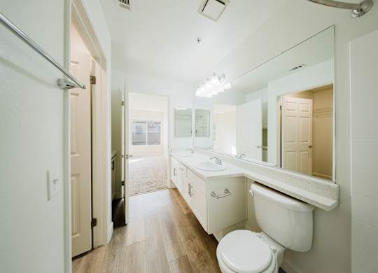 A white bathroom with a toilet, sink and mirror. at Legends at Rancho Belago, Moreno Valley, 92553