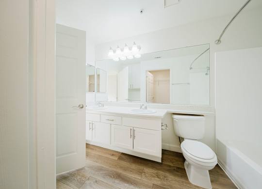 A white bathroom with a toilet, sink, and mirror. at Legends at Rancho Belago, Moreno Valley