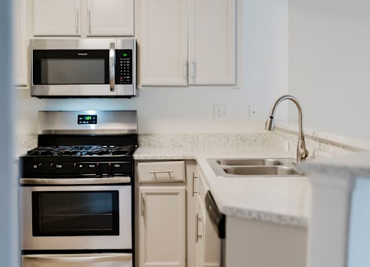 A modern kitchen with a stove, oven, microwave, and sink. at Legends at Rancho Belago, California