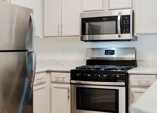 A modern kitchen with a stainless steel refrigerator, microwave, and stove. at Legends at Rancho Belago, Moreno Valley, CA