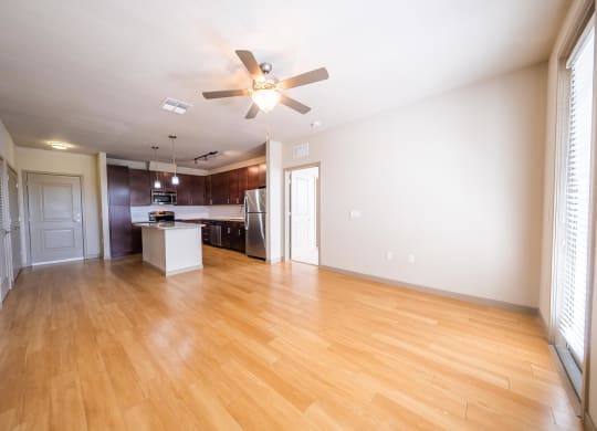 an empty living room and kitchen with wood flooring and a ceiling fan at Azul Baldwin Park, Florida