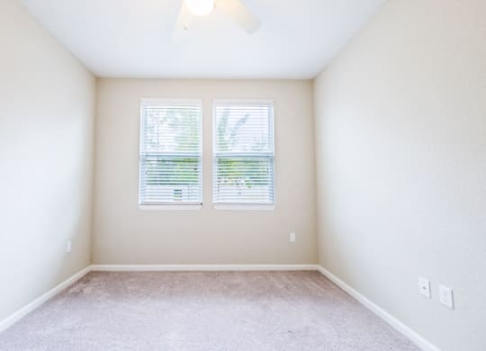 an empty room with two windows and a carpeted floor at Linden on the GreeneWay, Florida