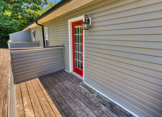 the front deck of a house with a red door at Ashford Place Apartments, Kannapolis