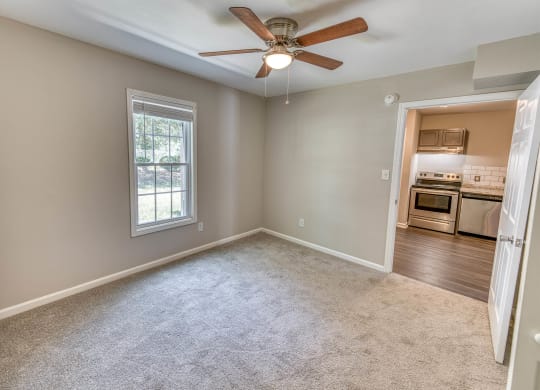 an empty living room with a ceiling fan and a window at Ashford Place Apartments, North Carolina