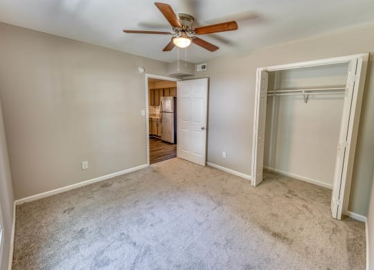 a bedroom with a ceiling fan and a door to a closet at Ashford Place Apartments, Kannapolis, NC