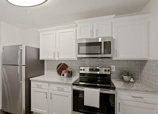 a kitchen with stainless steel appliances and white cabinets at The Fields of Manassas in Lorton, VA
