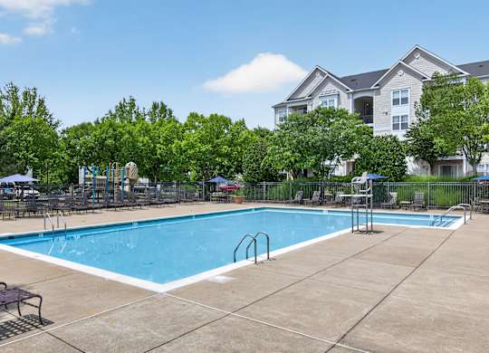 A large swimming pool surrounded by trees and apartment buildings.