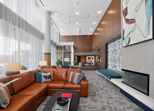 A modern living room with a brown leather couch and a fireplace.