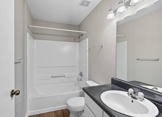 A white bathroom with a toilet, sink, and shower. at Greens at Stonecreek, Lithonia, GA