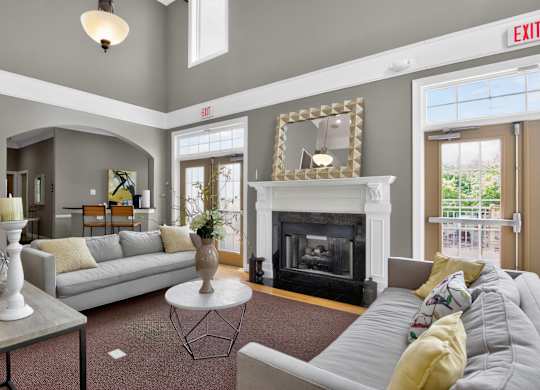A living room with a grey couch, a fireplace, and a mirror on the wall.