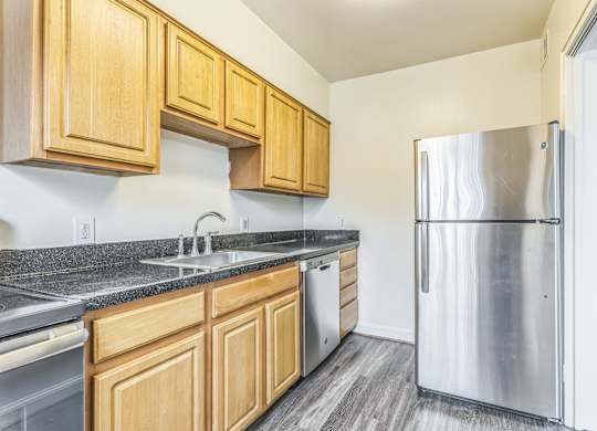 A kitchen with wooden cabinets and a stainless steel refrigerator.