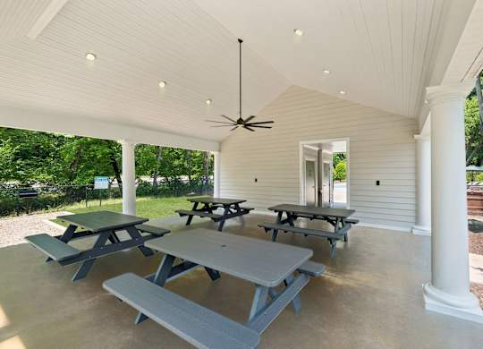 A covered patio with tables and benches at The Overlook at Quantico Apartments, Triangle, VA, 22172