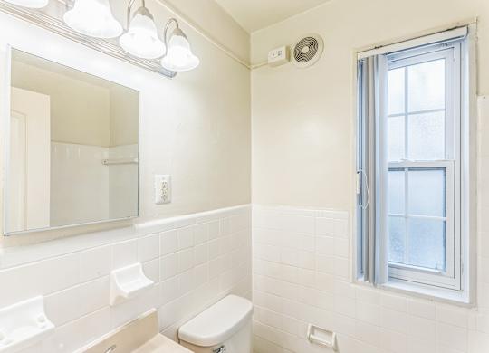 A white bathroom with a toilet, sink, and mirror.