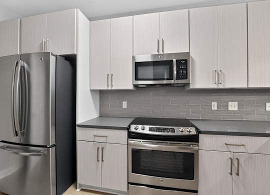 A kitchen with a refrigerator, oven, and microwave.