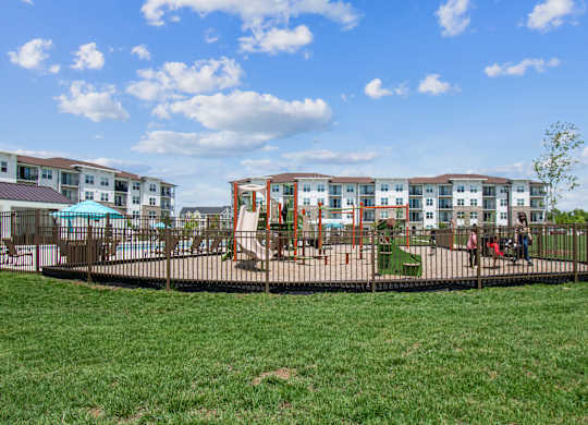 A playground with a swing set and a building in the background.