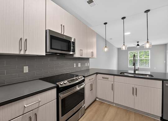 A modern kitchen with a black countertop and white cabinets.