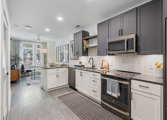 a modern kitchen with black and white cabinets and stainless steel appliances at Hawkins Press Apartments North Carolina
