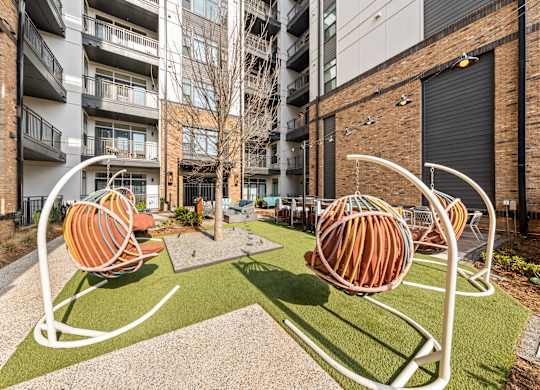 A playground with two orange and white swings at Hawkins Press Apartments, Charlotte, NC, 28203