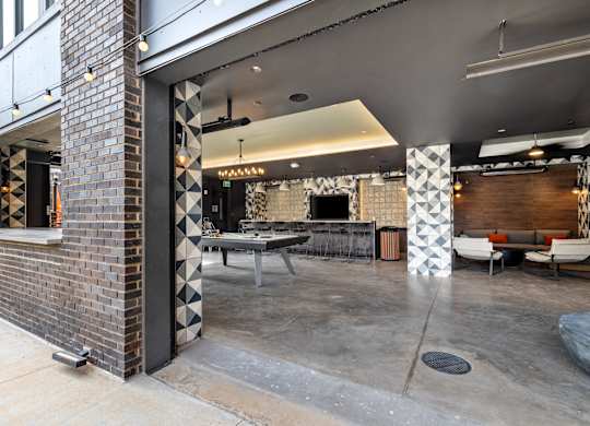 A modern outdoor seating area with a brick wall and patterned columns at Hawkins Press Apartments, Charlotte, North Carolina