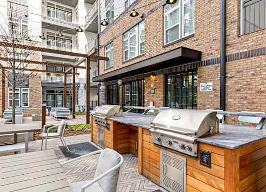 A wooden BBQ grill is in the middle of a patio at Hawkins Press Apartments, Charlotte, NC