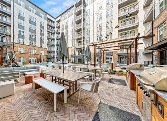A patio area with tables and chairs surrounded by buildings at Hawkins Press Apartments, Charlotte